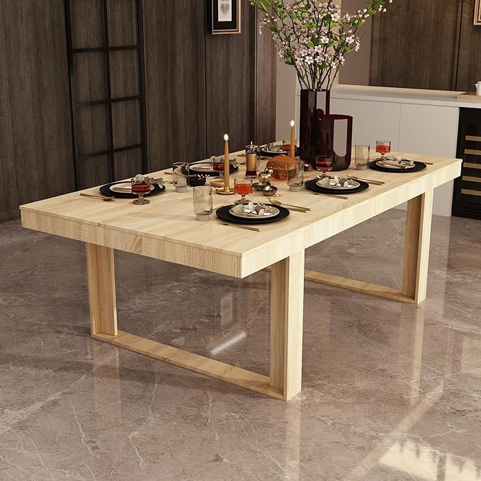 Light wood Japandi dining table set with black plates, glassware, and a vase of blooming branches.