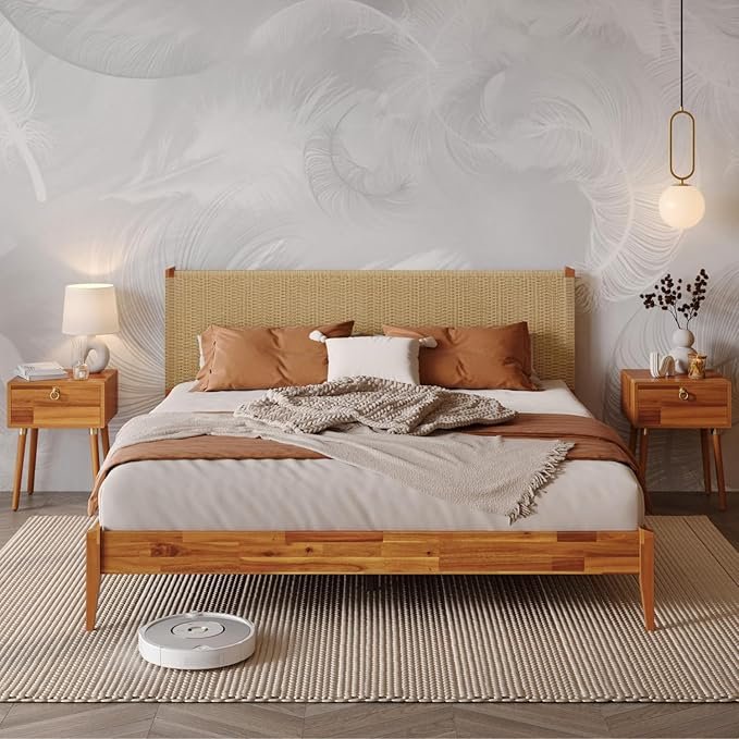 Organic modern bedframe with woven rattan headboard, warm acacia wood frame, rust-colored pillows, and soft neutral bedding in a light, textured bedroom.