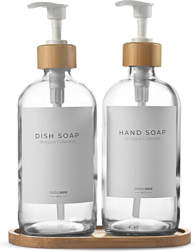 Clear glass soap and hand wash dispensers with bamboo pumps on a matching tray, creating an organized Japandi kitchen sink area.