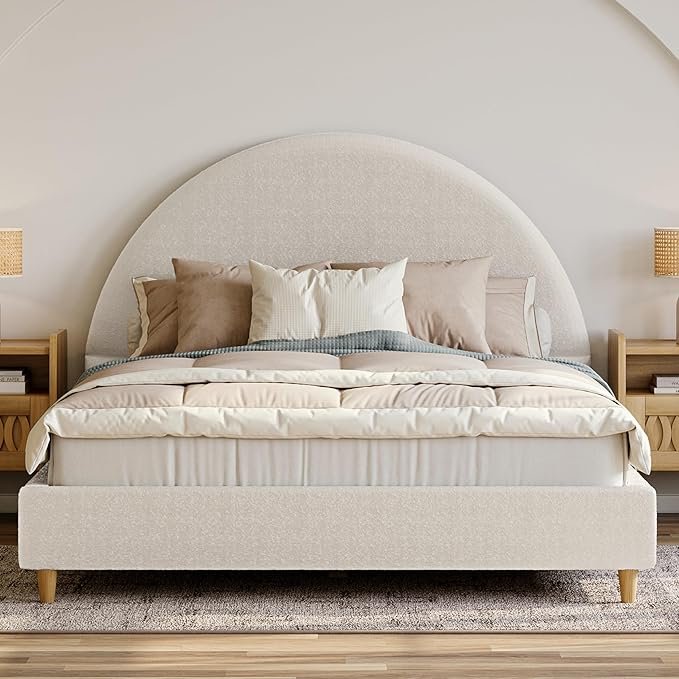 Organic modern bedframe with oversized arched upholstered headboard, layered neutral bedding, and wood nightstands in a minimalist bedroom.