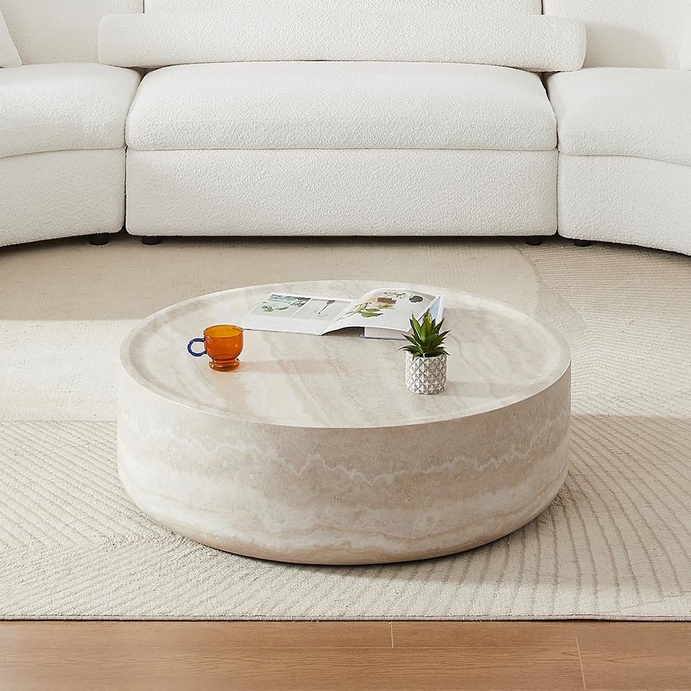round travertine coffee table in neutral modern living room with white sofa