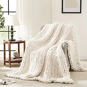 Soft cream chunky knit throw blanket draped over an armchair for warm and cozy fall decorating.