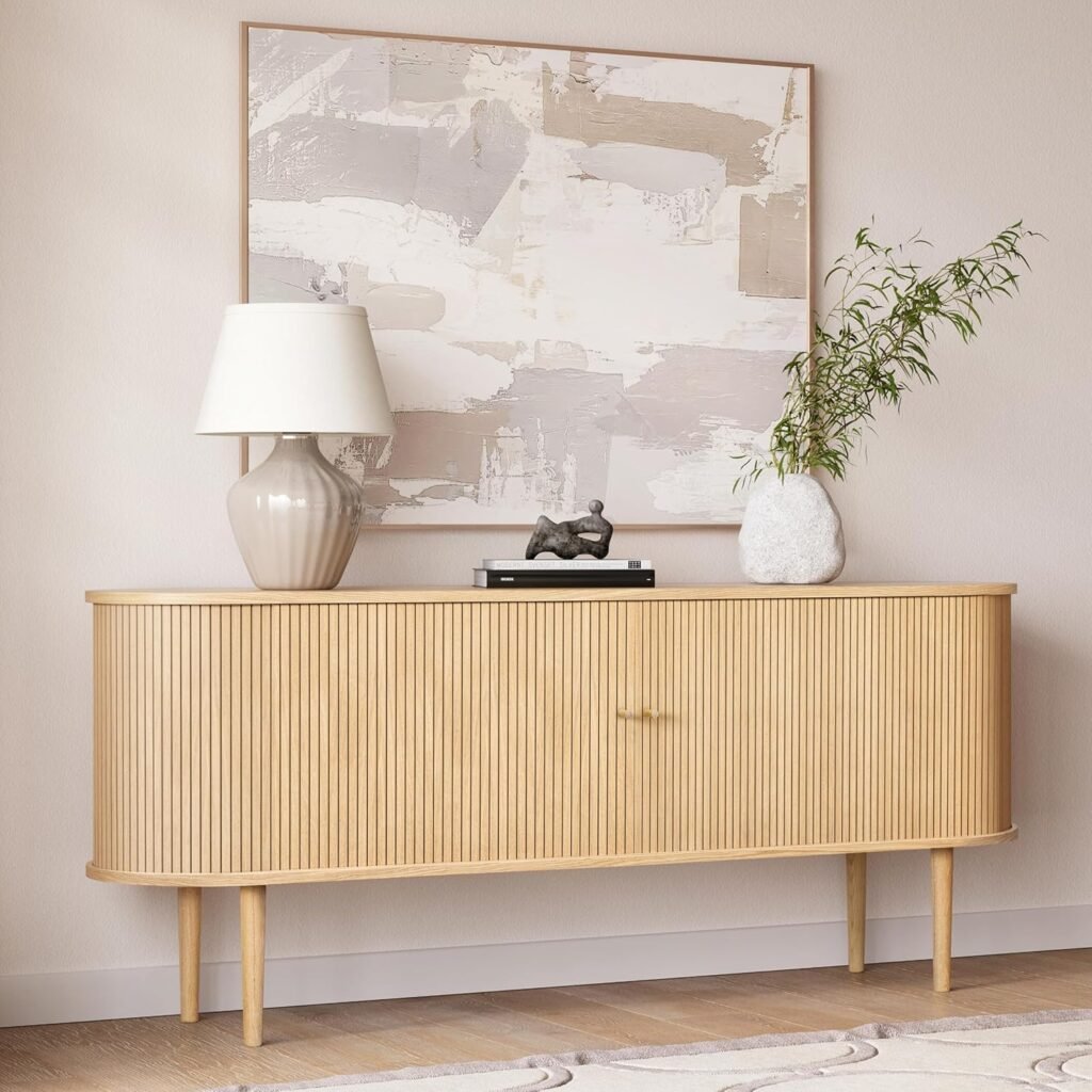 Light wood Japandi sideboard with vertical ribbed design, styled with neutral artwork, a ceramic lamp, and a textured vase with greenery.