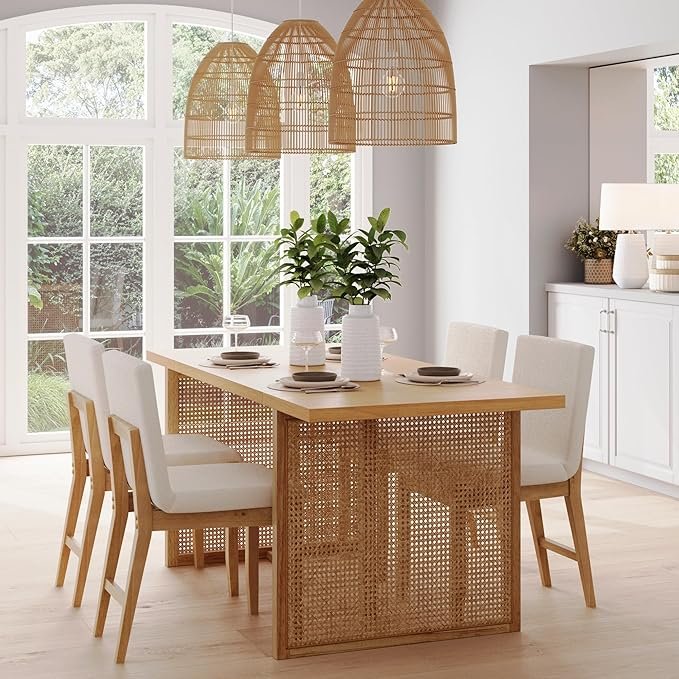 Japandi dining room with light wood dining table featuring cane paneling, paired with white upholstered chairs and rattan pendant lights.
