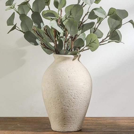 Textured ceramic vase filled with faux branches, styled on a wooden table for Japandi home decor.