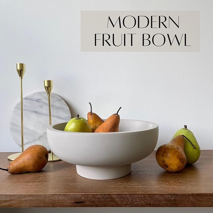 Minimalist white ceramic fruit bowl filled with pears, styled on a wooden table with gold candlesticks and a marble trivet.