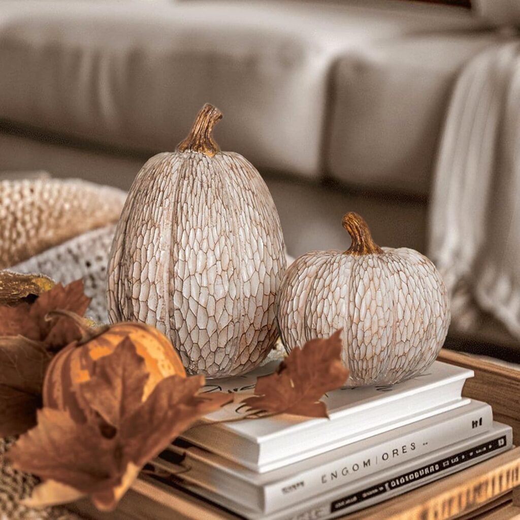 two neutral decorative pumpkins with textured finish styled on coffee table books for fall decor