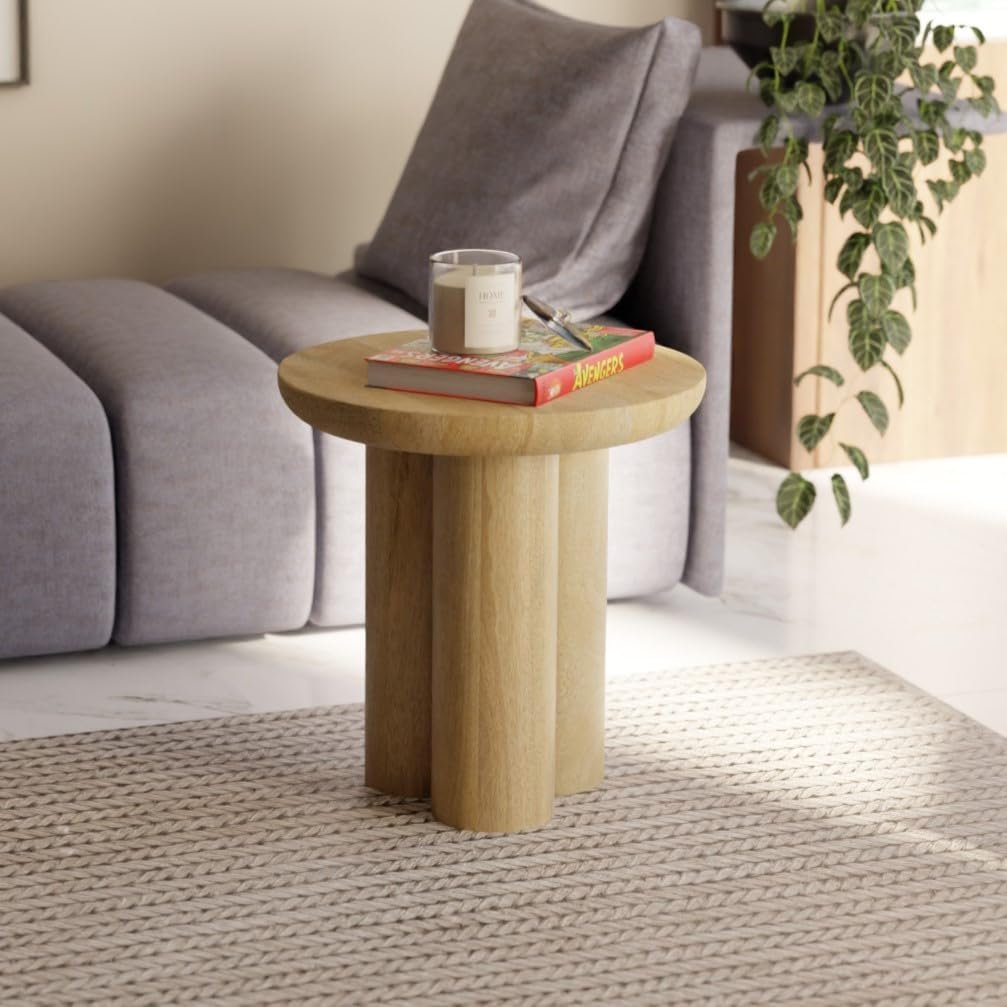 Sculptural Japandi side table with round top and chunky cylindrical legs, styled with a candle and magazine on a neutral rug.