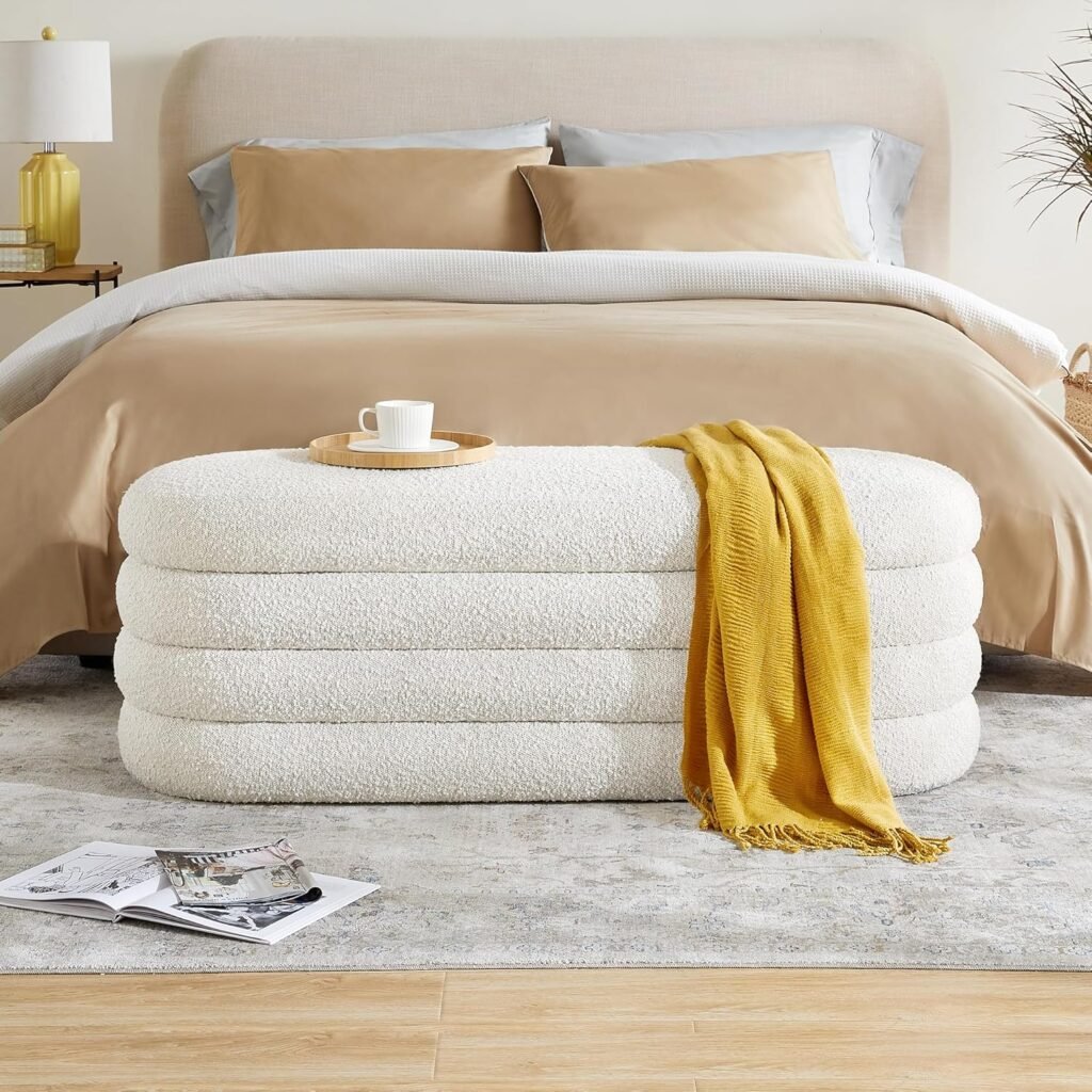white bouclé storage bench at the end of a bed with neutral bedding and cozy throw