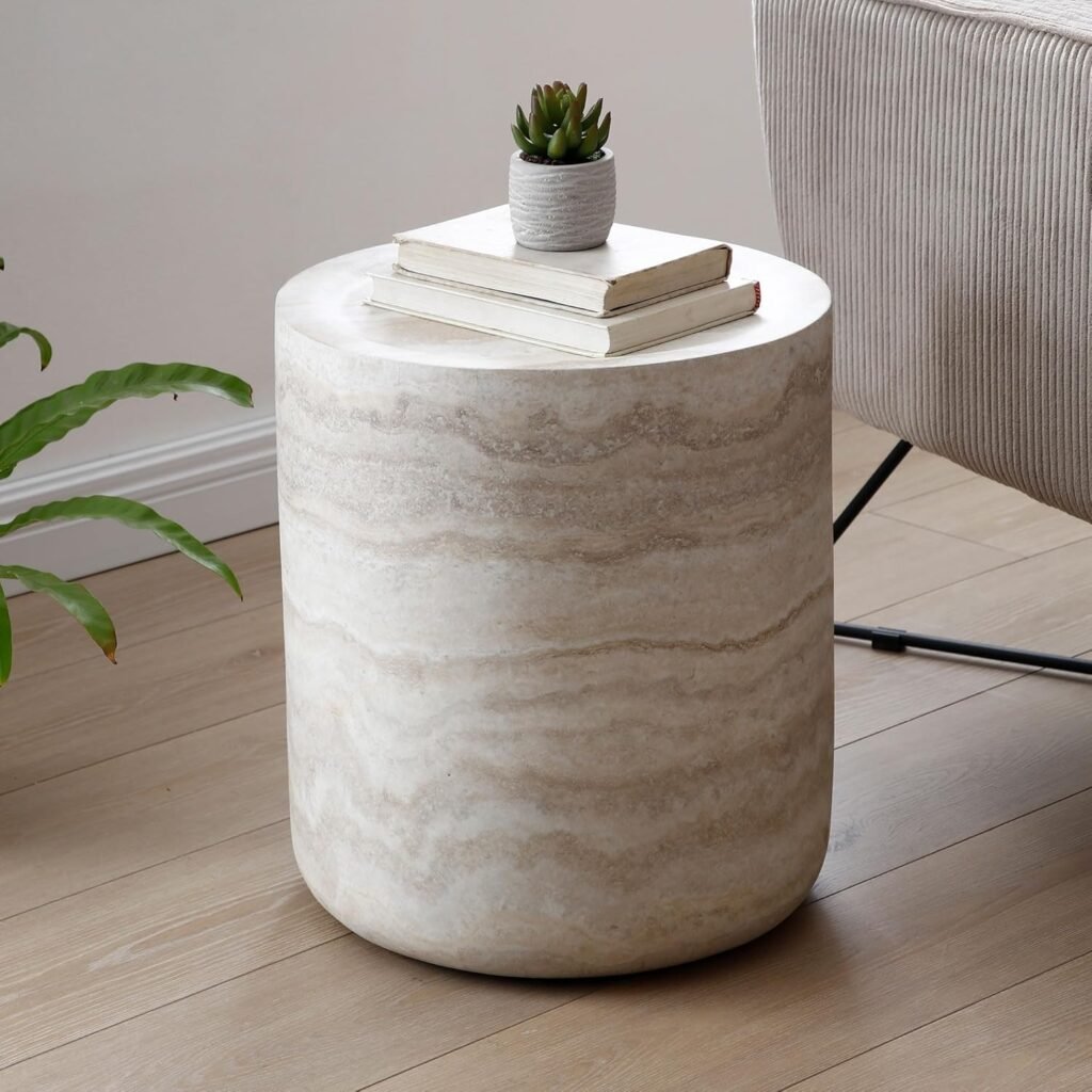round travertine stone side table styled with books and a small plant in a minimalist living room