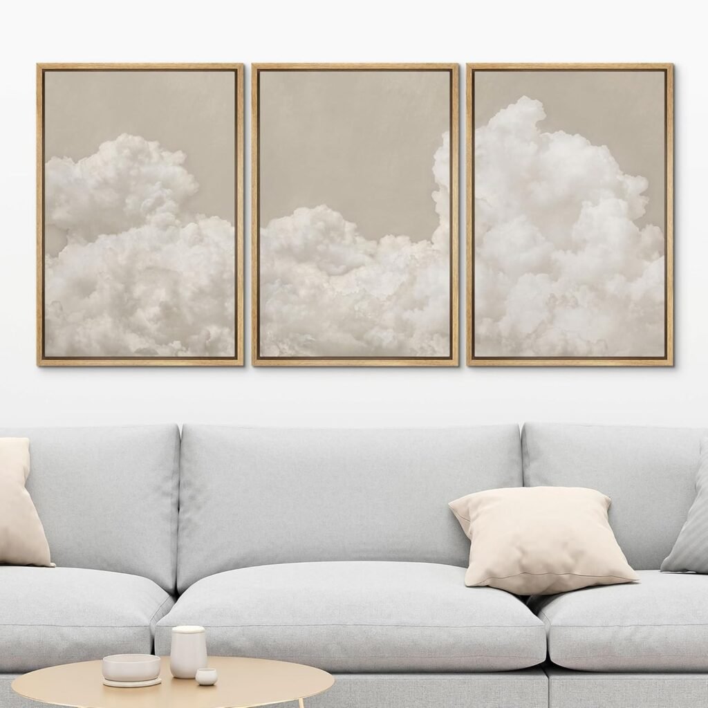 three framed neutral cloud art prints hung above a light gray sofa with minimalist pillows