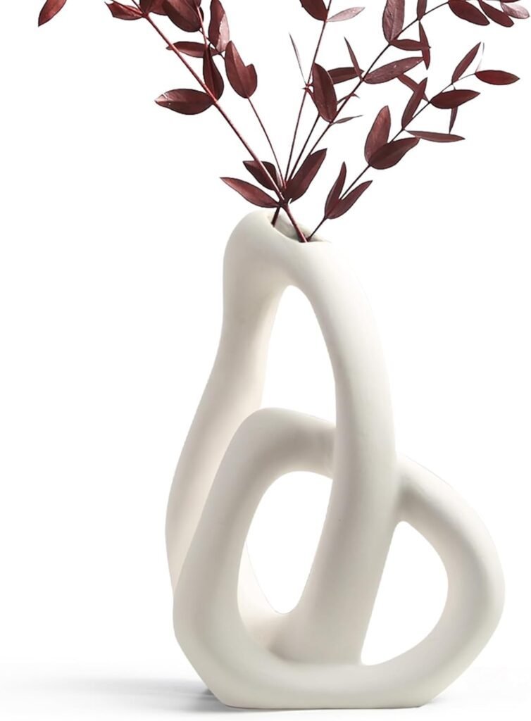 modern sculptural white ceramic vase with abstract loops styled with greenery